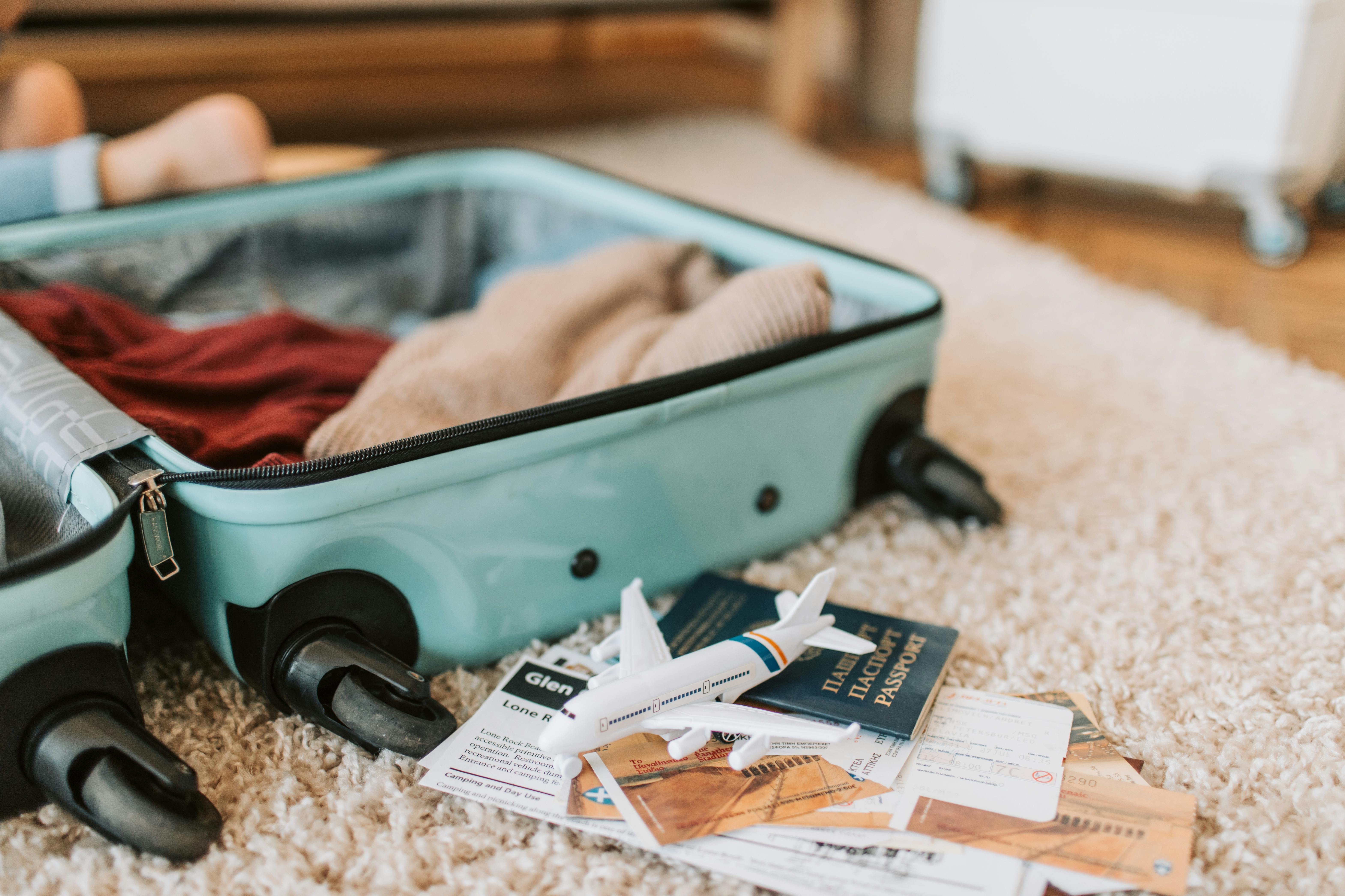 Open suitcase with clothes, toy airplane, passport, and tickets, ready for an adventure